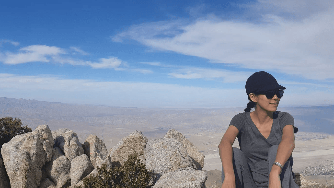 Megan Chen sitting on a mountain overlook