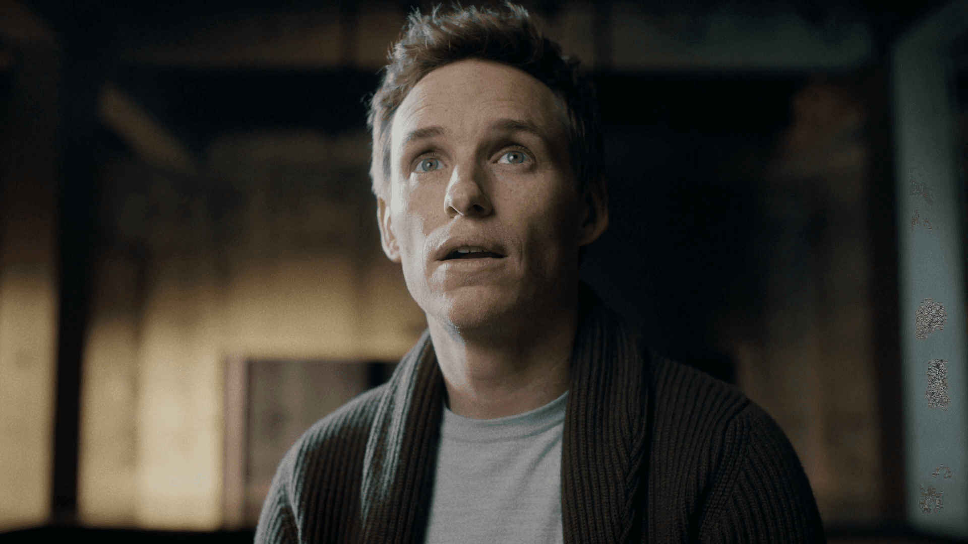 A man looking upward in a warmly lit cinematic interior