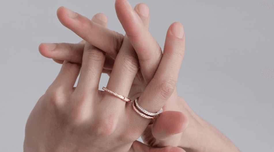 Interlaced hands wearing fine gold and diamond rings